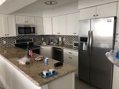 a kitchen with stainless steel appliances and granite counter tops, along with white cabinetry