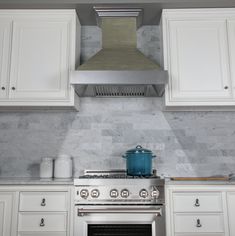 a stove top oven sitting inside of a kitchen next to white cupboards and drawers