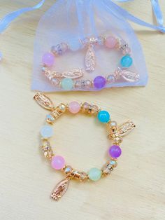 two bracelets on a table next to a bag with beads and charms in it