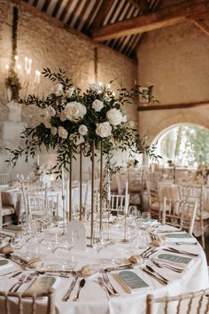 a table set up with white flowers and place settings