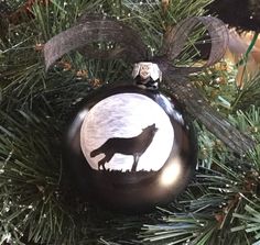 a black and white ornament with a wolf on it's side hanging from a christmas tree