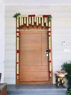 an entrance to a building decorated with red and white flowers, greenery and pom poms