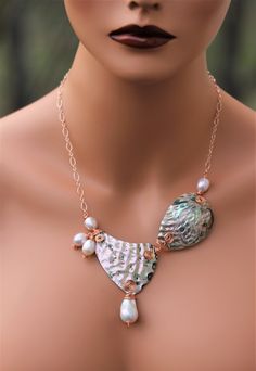 P36 Absolutely Stunning Genuine hand carved Abalone Shell set with Genuine Edison Pearls on Hammered Copper Necklace These shells have been hand carved and wire wrapped in our studio in Texas This unique jewelry is one of a kind and will never be replicated. Spec: Material: Genuine Abalone shell Origin of Pearl: New Zealand, Japan, Chile, Africa Colors: Intense iridescent Gold, Green, Pink, with some Blue undertone Bottom Pearl: White Baroque Freshwater Pearl Top Pearl Color: White with some Pink and Gray Blue undertone Back of the top pearl: Flat with natural ripple from the oyster  Other Pearls:  Pearl quantity: 4 Pearls Pearl color: White with Gray, Pink, and Blue under hue  Wire Wrap: 100% Copper Chain: 14KR Gold fill Chain link on the inside: 16 inches with a 2-inch extender with a Pe Abalone Shell Necklace, Beach Wedding Jewelry, Top Pearl, June Birthday, Jewelry Beach, Seashell Jewelry, Bold Jewelry, Shell Necklace, Shell Jewelry