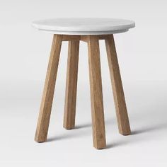 a white stool with wooden legs and a round seat on the top, in front of a plain background