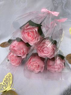 pink roses are wrapped in clear cellophane and placed on a white tablecloth