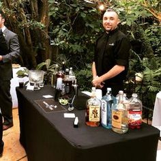 two men standing behind a table with bottles of alcohol on it