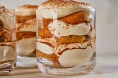 two glasses filled with desserts sitting on top of a table