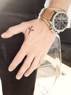 a person with a cross tattoo on their left hand