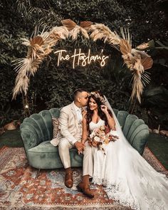 a bride and groom sitting on a couch in front of a sign that says the fabulouss