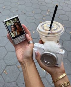 a person holding up a cell phone next to a cup with a drink in it