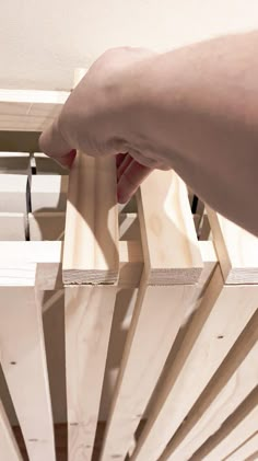 a person is holding something in their hand over the top of a wooden structure that has slats attached to it