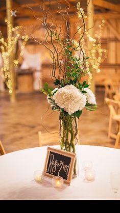 an arrangement of flowers and greenery in a vase on a table