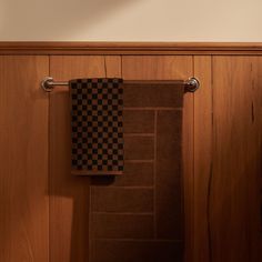 two towels are hanging on the wall next to a towel rack in a wood paneled bathroom