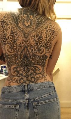 the back of a woman's body with intricate tattoos on her upper and lower back