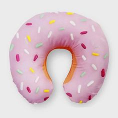 a pink donut shaped pillow with sprinkles on it's side