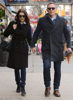 a man and woman walking down the street holding hands