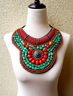 "Stunning handmade Tibetan bib collar necklace in faux teal green turquoise, coral and amber beads, with a stunning central brass medallion. Perfect with a flowing caftan or an itsy black bikini. Perfect anywhere you are barefoot! Wear your hair up, with a bright ribbon or turban, or wear it down! You don't need much else! Eye-catching geometric pattern with a mix of smooth and textured beads. This is a handmade reproduction of a Tibetan tribal neck piece or Skeypuk, which is worn as collars on Red Bohemian Bib Necklace For Festivals, Handmade Turquoise Bib Necklace With Round Beads, Handmade Bohemian Green Turquoise Necklace, Bohemian Red Bib Necklace With Round Beads, Handmade Green Turquoise Bohemian Necklace, Bohemian Green Handmade Turquoise Necklace, Handmade Turquoise Bohemian Bib Necklace, Bohemian Turquoise Bib Necklace With Colorful Beads, Handmade Beaded Necklaces For Festivals