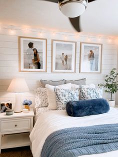 a bedroom with pictures on the wall above the bed and below the bed is a blue throw pillow