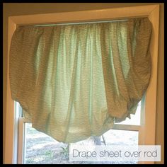 a green curtain hanging from the side of a window in front of a window sill