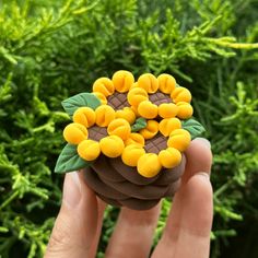 a hand is holding a small toy with yellow flowers on it