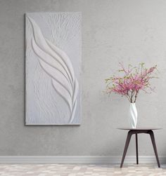 a vase filled with pink flowers sitting on top of a table next to a white wall