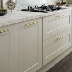 a white kitchen with marble counter tops and gold pulls on the cabinet doors is shown