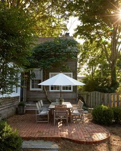 a patio with an umbrella and table in front of a house on a sunny day