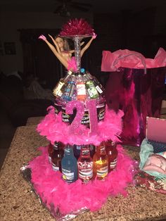 a table topped with lots of bottles and pink feathers next to a bag filled with liquor