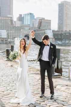 a bride and groom dancing together in front of the water