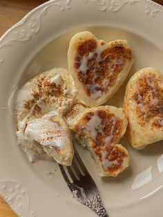 three heart shaped pastries on a plate with a fork