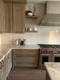 a kitchen with wooden cabinets and marble counter tops, along with stainless steel oven hoods