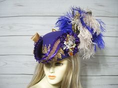 One-of-a-kind PURPLE NOT BLUE woolen pirate hat with golden venise lace, purple pleated trim and matching braid. Purple not blue and beige ostrich feathers, two black and gold feathers tucked in, a 4" sparkly crowned rhinestone skull accent and two satin bows. Perfect for any pirate event. Please measure your head as I cannot make this hat bigger. This hat is 22.5" for the inside circumference with a built-in hat sizer. Just cinch and tie. This is not an oversized brim pirate hat. The upturn brim is about 4". International buyers are responsible for custom fees as it is not included in the shipping. Please Click on the shipping tab to calculate shipping so there are no surprises over shipping.    ALL SALES ARE FINAL!!! NO EXCHANGES! NO REFUNDS! ASK QUESTIONS AHEAD OF TIME AS ALL SALES ARE Purple Pirate, Rhinestone Skull, Pirate Hat, Steampunk Hat, Pirate Hats, Gold Feathers, Jack Sparrow, Costume Hats, Ostrich Feathers