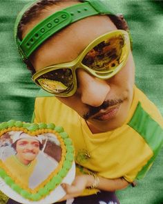 a man wearing sunglasses holding a cake in front of his face with a photo on it