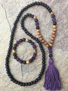 108 bead mala & bracelet 108 bead mala with 100% Egyptian cotton, handmade tassel. Made with: Matte black wooden beads (8mm), brown robles wood beads (8mm), Lava rock (8mm), matte purple glass beads (8mm) These 108 beaded necklace measures 29 inches in lengthThe total hanging length is 18 inches. Tassel is 2.5 inches The symbol of the Buddha, with his compassionate smile, reminds us to strive to develop kindness, peace & love so that we can be a true friend to all beings. Lava stone is o Spiritual Wooden Beads Jewelry For Meditation, Holistic Round Beads Jewelry For Yoga, Holistic Jewelry With 8mm Beads For Yoga, Spiritual Round Bead Jewelry For Yoga, Spiritual 108 Beaded Jewelry For Yoga, Spiritual Jewelry With 108 Beads For Yoga, Holistic Yoga Jewelry With 108 Beads, Holistic 108 Beads Jewelry For Meditation, Holistic Jewelry With 108 Beads For Meditation