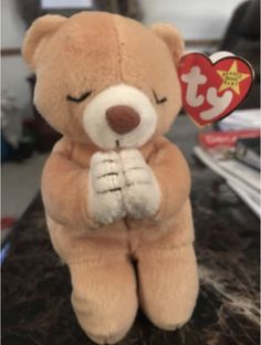 a brown teddy bear sitting on top of a counter next to a red and white heart