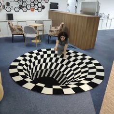 a woman standing on the floor in front of a black and white rug