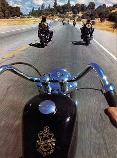 three people riding motorcycles down the road in front of another motorcyclist on a motorcycle