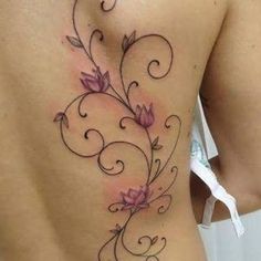 the back of a woman's stomach with flowers and swirls tattooed on it