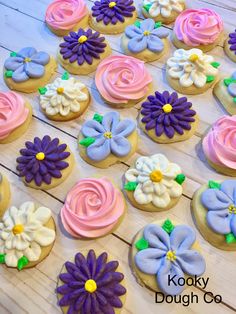 many decorated cookies on a wooden table with flowers and swirls in the icing