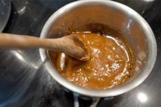 a wooden spoon in a saucepan on top of a stove with some brown liquid