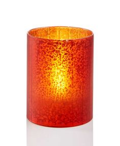 an orange glass candle holder on a white surface