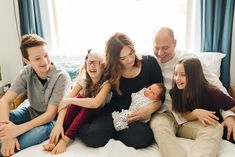 a group of people sitting on top of a bed with a baby in their arms