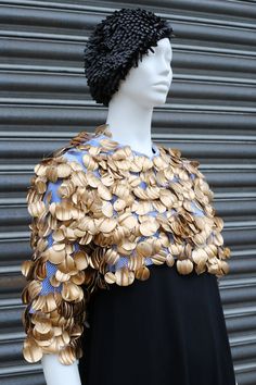 a mannequin with gold coins on it's chest and black dress underneath