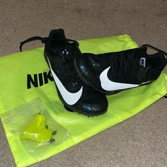 a pair of black and white nike shoes sitting on top of a yellow towel next to a bag