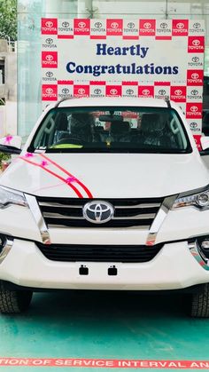 a white car parked in front of a red and white sign that says hearty congratulationss