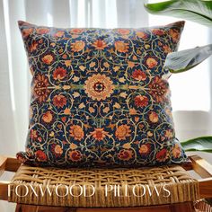 a pillow sitting on top of a wicker chair next to a potted plant