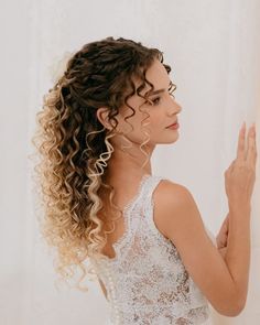 a woman with curly hair wearing a white dress and holding her hand up to the side