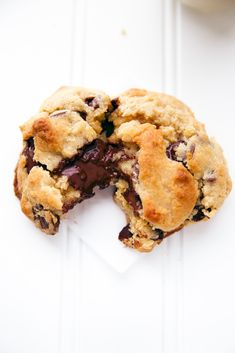 a chocolate chip cookie is cut in half on a white surface with a bite taken out