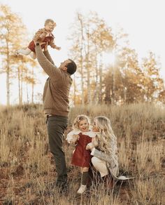 a man holding a child up in the air while standing next to two other people