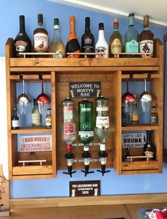 an assortment of liquor bottles are on display in a wooden cabinet with glassware and signs